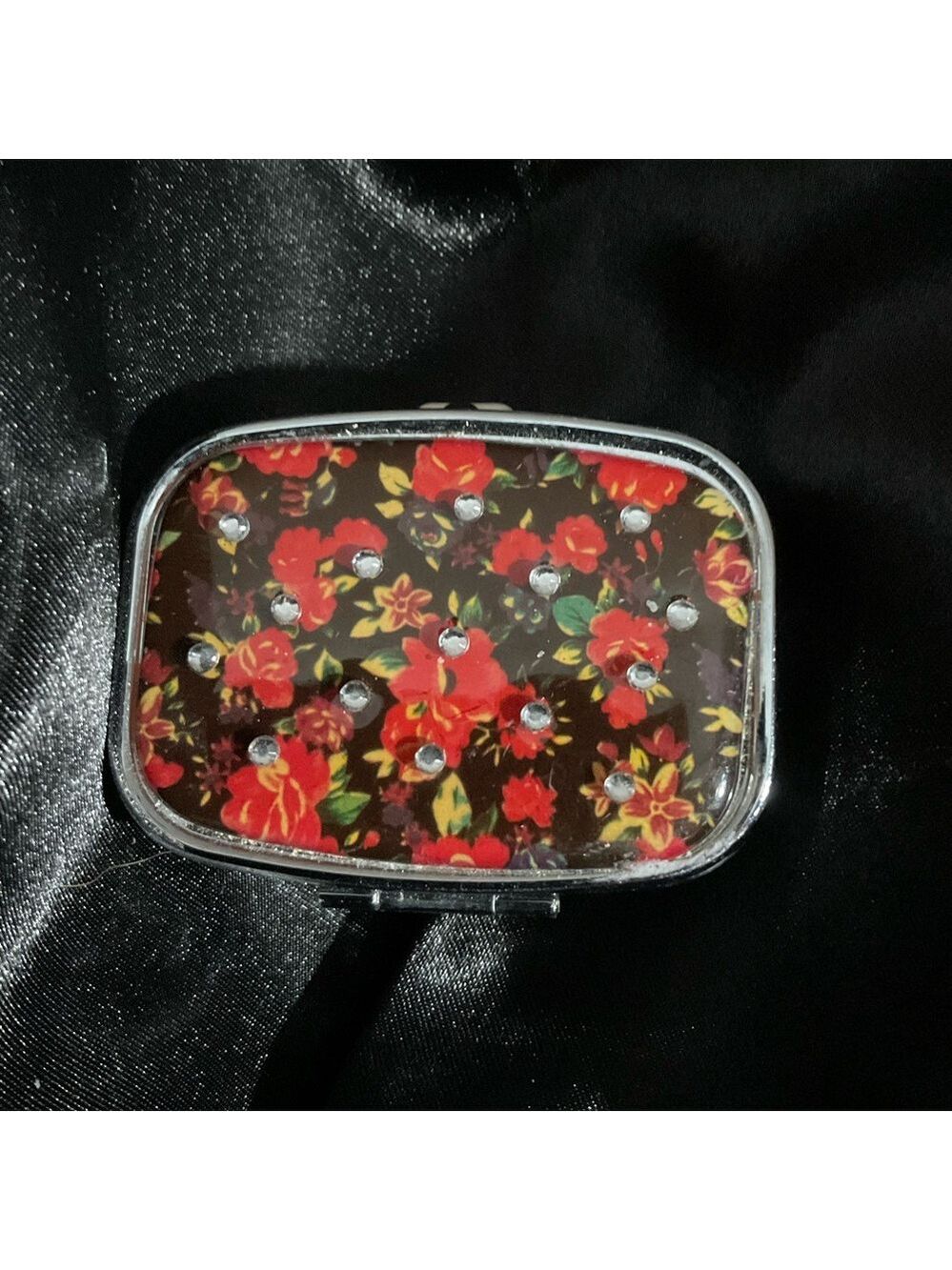 A compact, metal, floral-patterned pill case or travel medicine organizer 2339